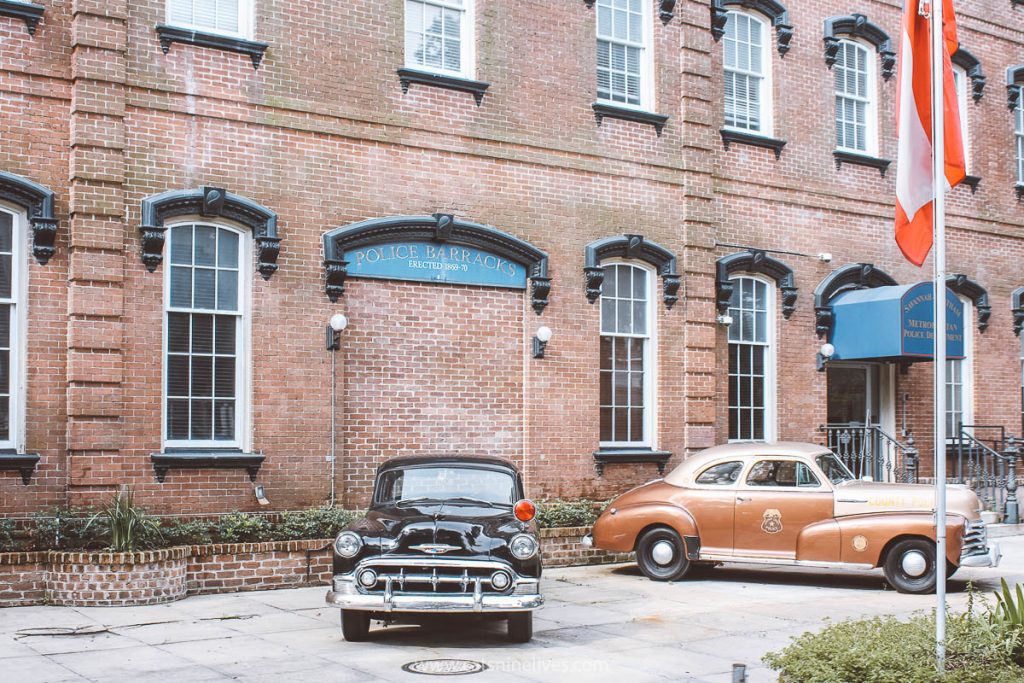 Two old cars parked outside the police station in the heart of historic Savannah