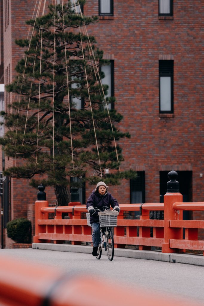 an older woman cycling through the streets of takayama