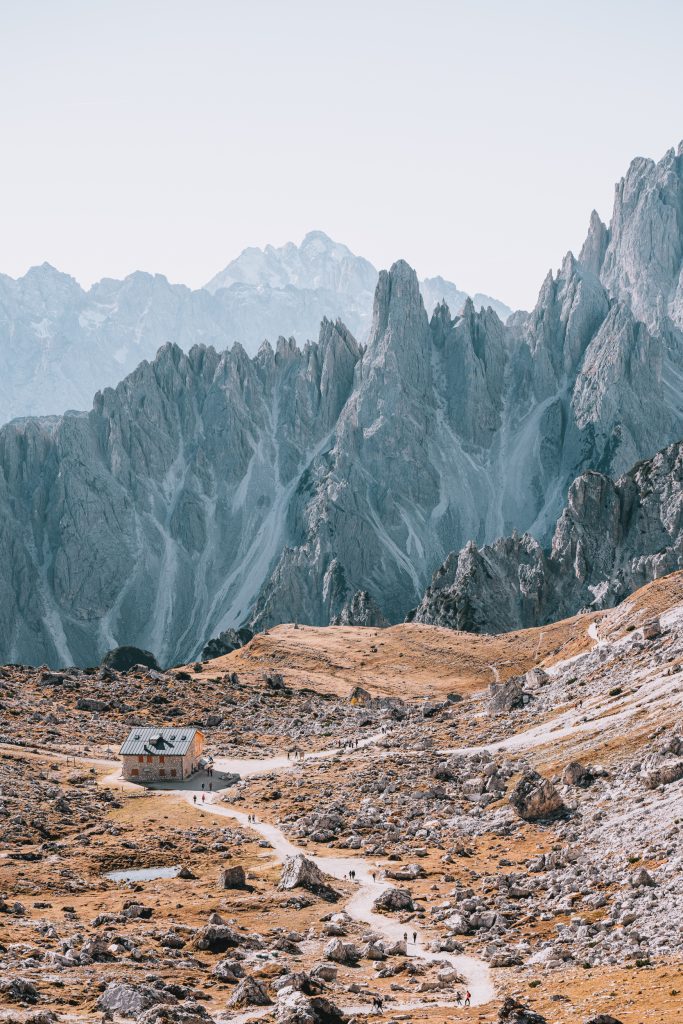 The small stone mountain hut or Rifugio Lavaredo with a hiking path leading to it and sharp mountain peaks in the background on the Tre Cime hike, one of my favourite things to do in the Dolomites