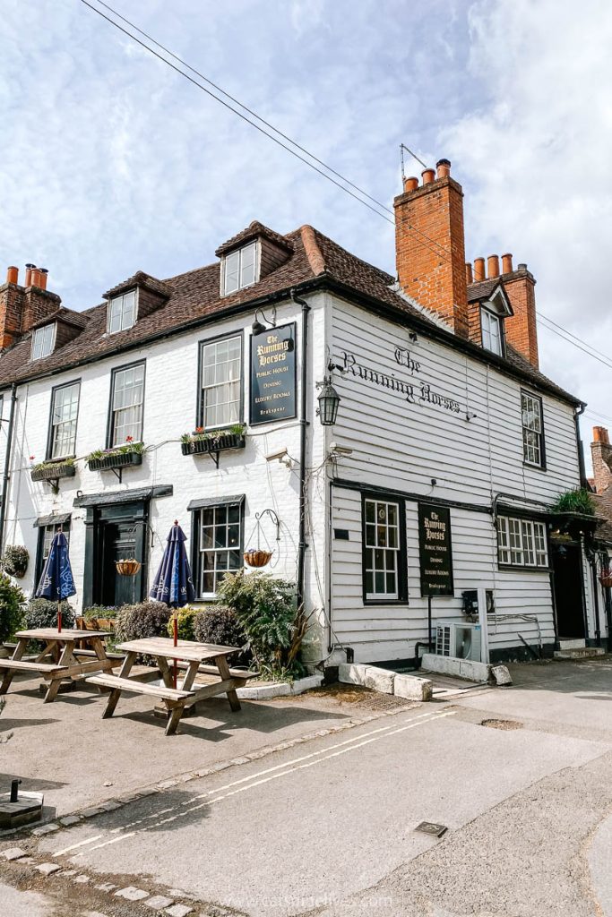 The Running Horses Pub, with white wood frontage and tables outside in Mickleham, Surrey