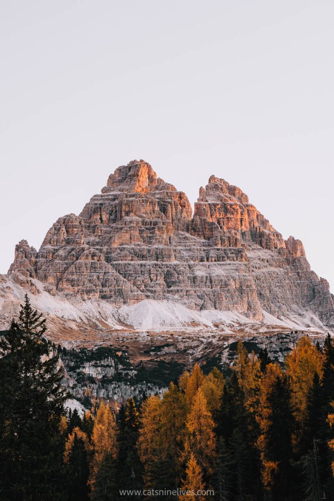 The peaks of Tre Cime with orange larch trees in the foreground - one of the main reasons one of my top tips for travelers to Italy is to visit in the autumn