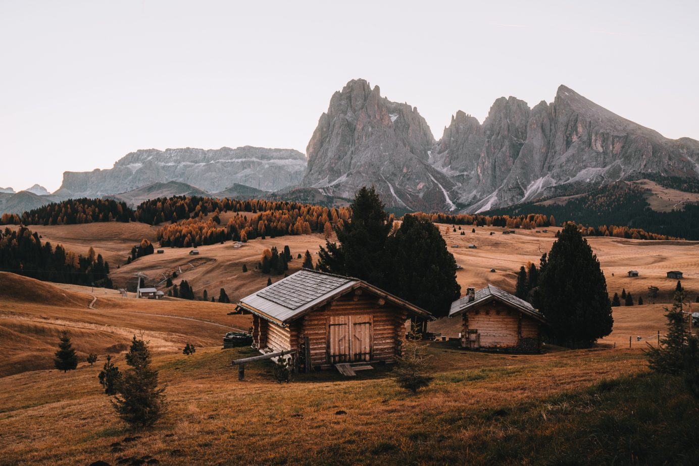 two small mountain huts with the peaks of the sassolungo massif in the background visited on a Dolomites itinerary