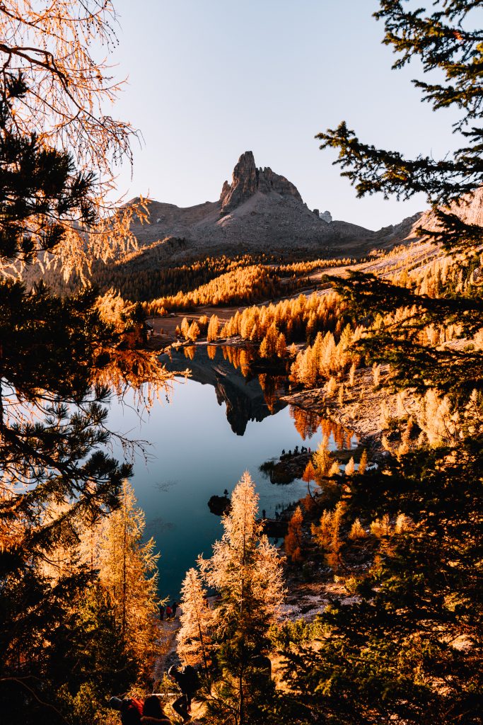 Golden sunrise at Lago di Federa with orange larch trees and a mountain peak reflected in the still water of the lake