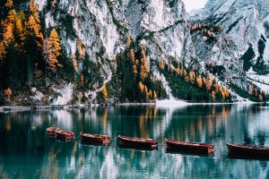 wooden rowboats reflected in the still blue water of lago di braies