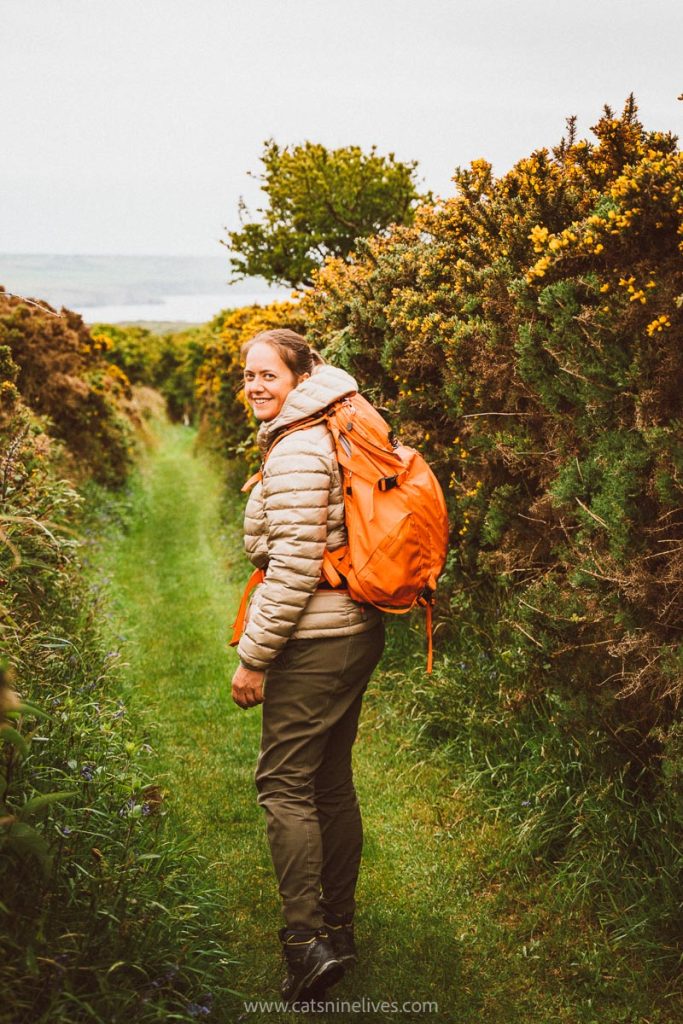 a women in hiking gear with a bright orange rucksack