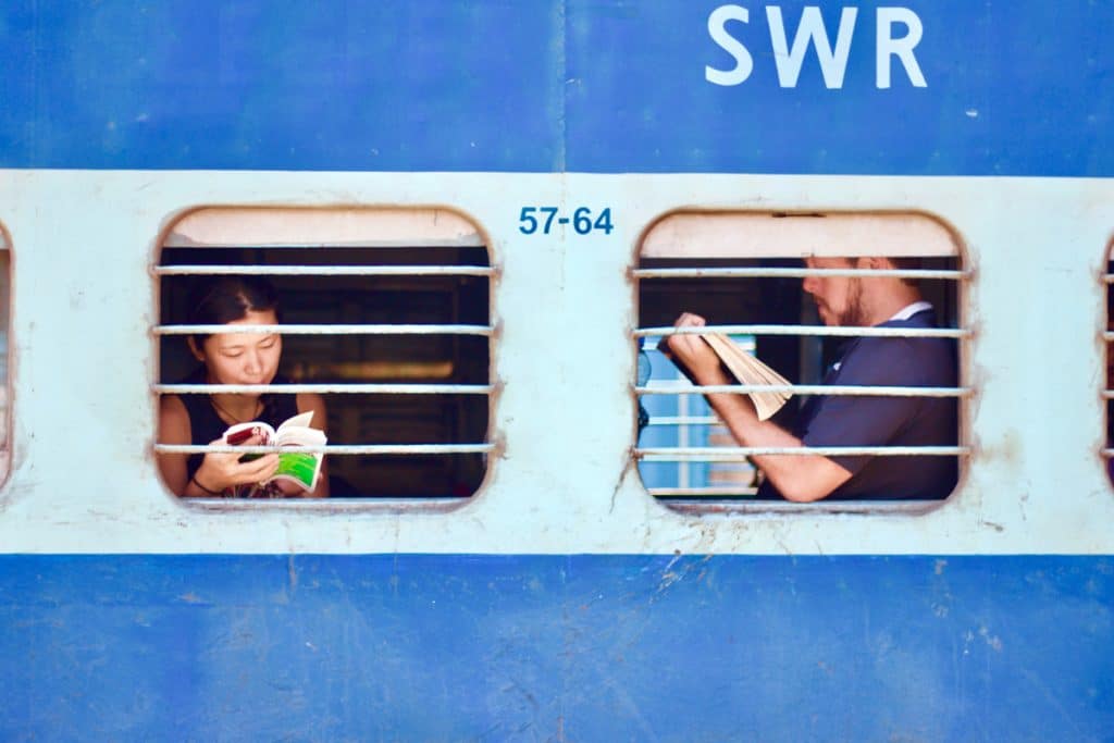 people reading by the window on a train which is one of the best sustainable travel transport options