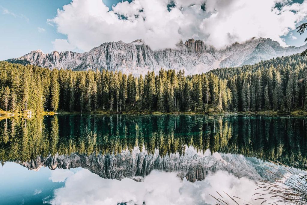 A perfect mirror image of pine trees and mountain peaks in a crystal clear mountain lake